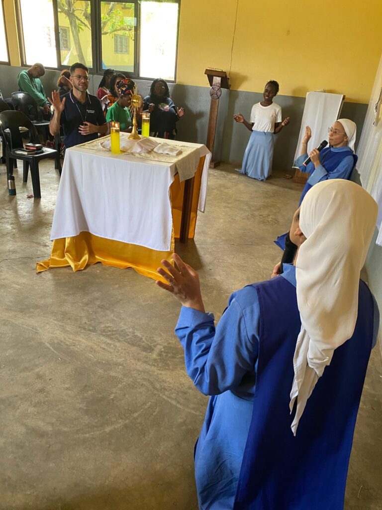 Missionária e participantes em oração diante do altar com o ostensório.
